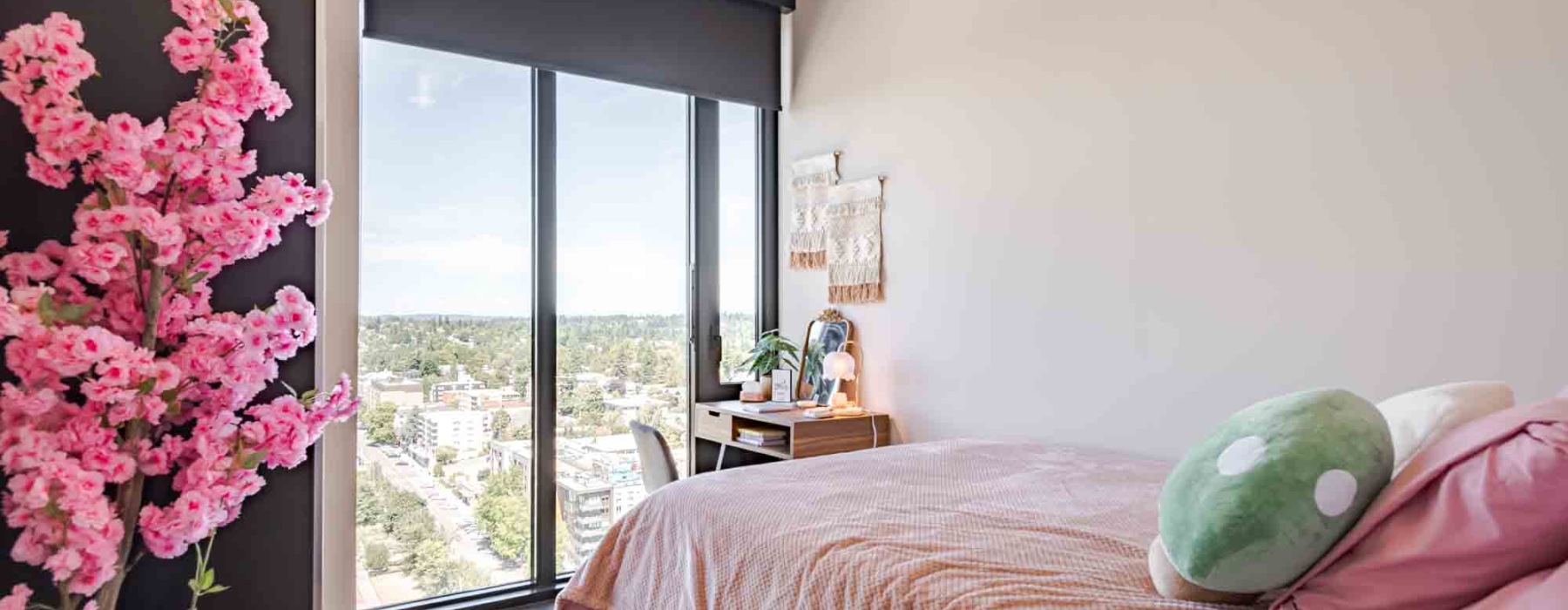 Model apartment bedroom also showcasing a full size bed, desk, chair, and dressers in our modern Seattle apartments with floor to ceiling windows.